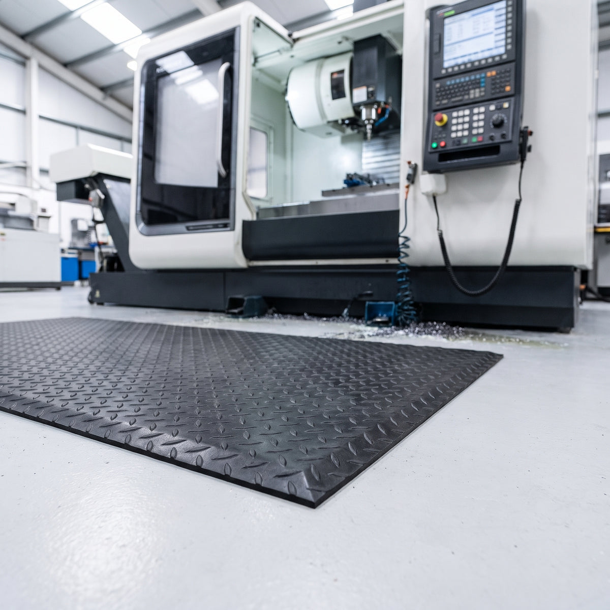 Black diamond plate anti fatigue mat in front of a CNC machining centre