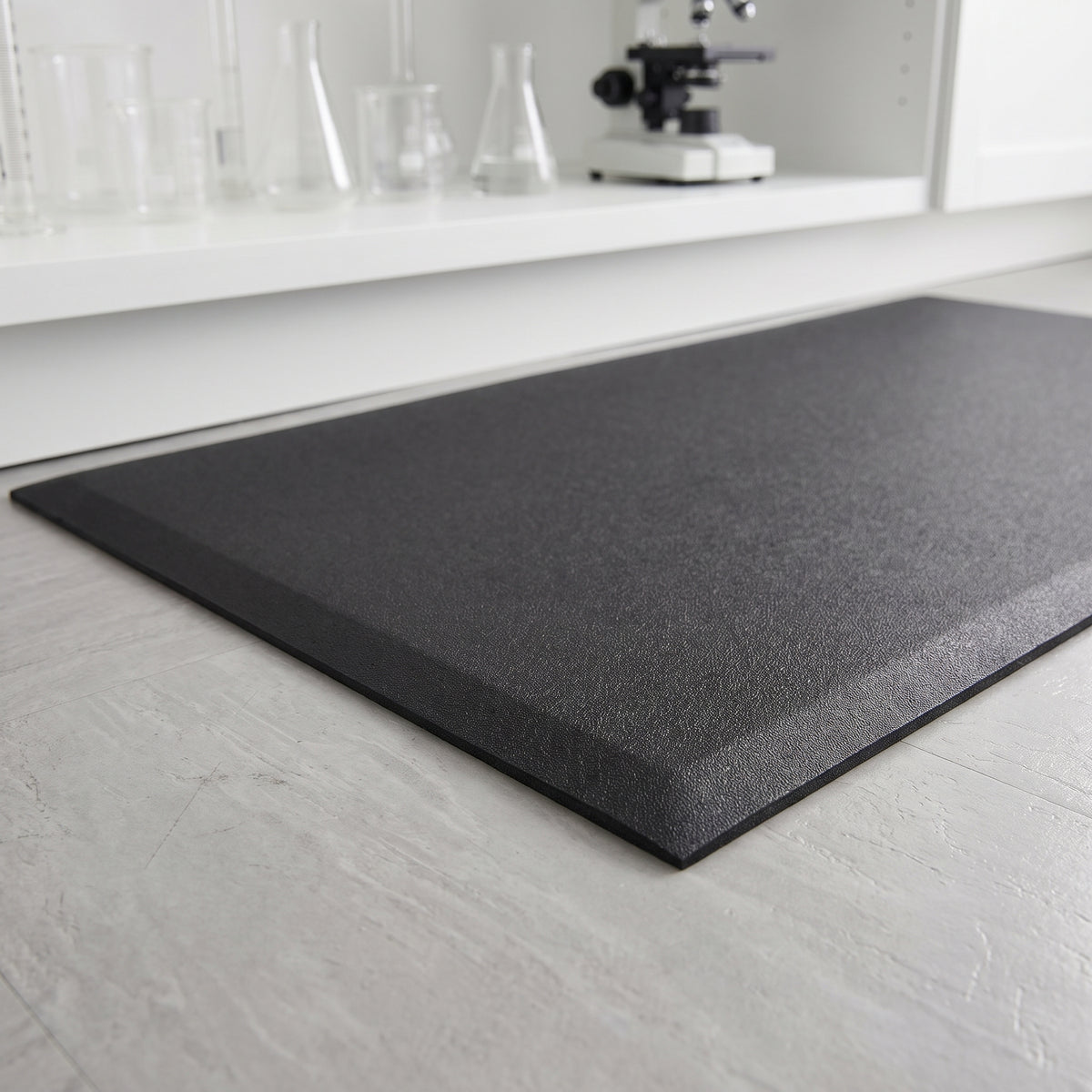 Black pebble texture anti fatigue foam standing mat with bevelled edges at a laboratory bench