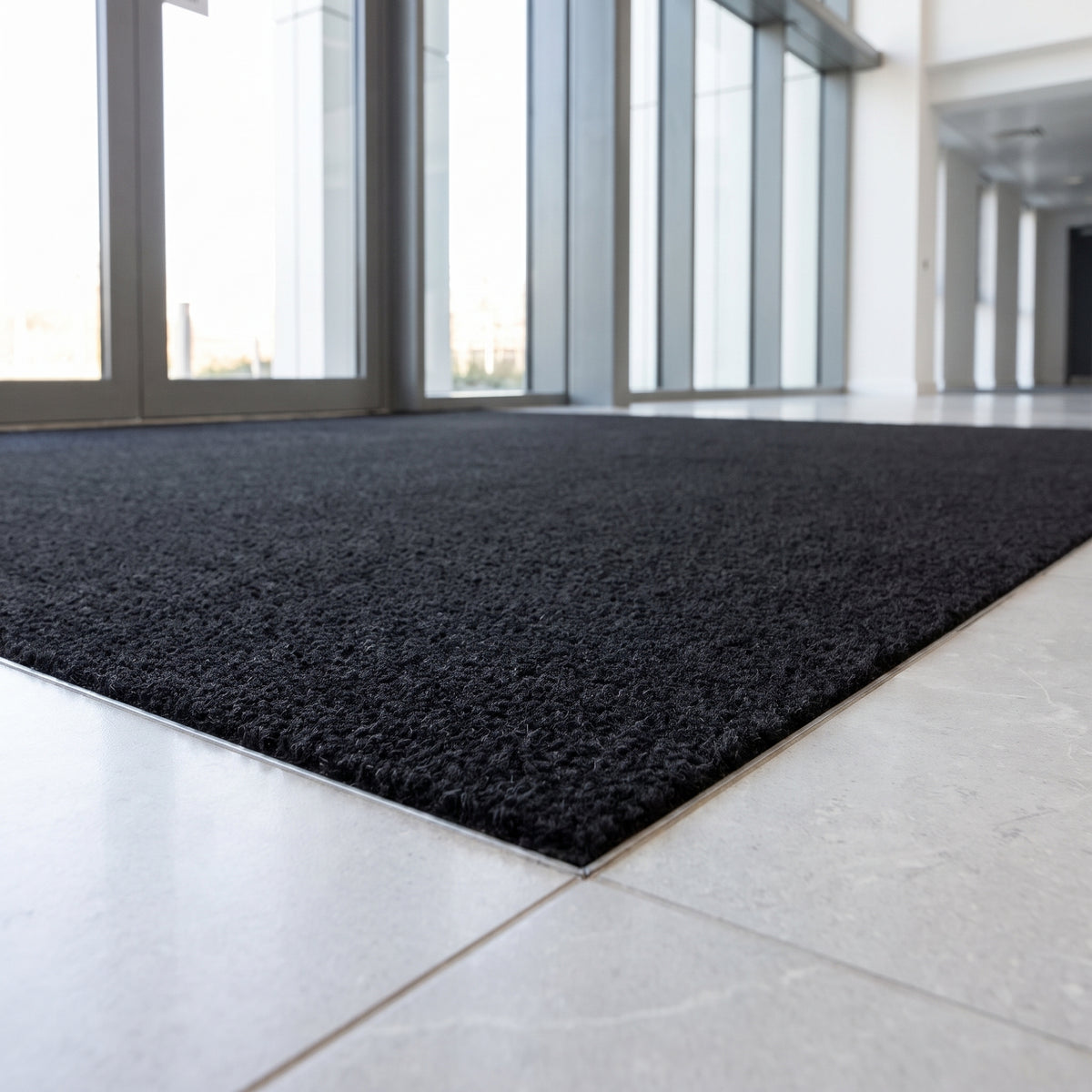 Black 17mm coir entrance matting in a recessed mat well at a corporate reception