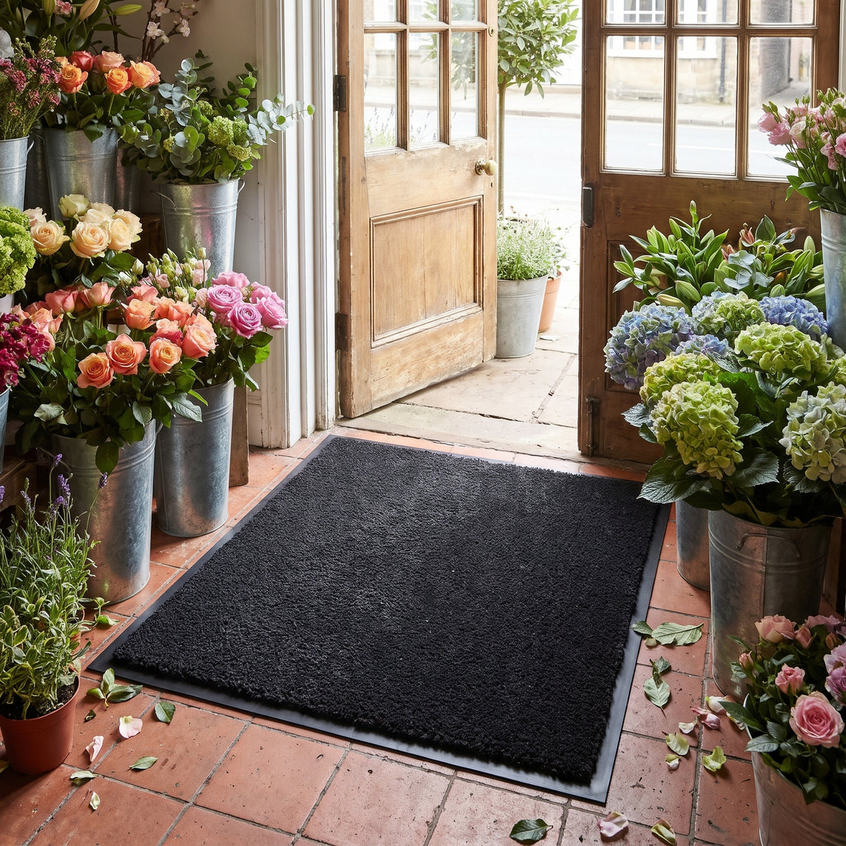 Black commercial made to measure entrance mat with rubber border in a high street florist shop doorway