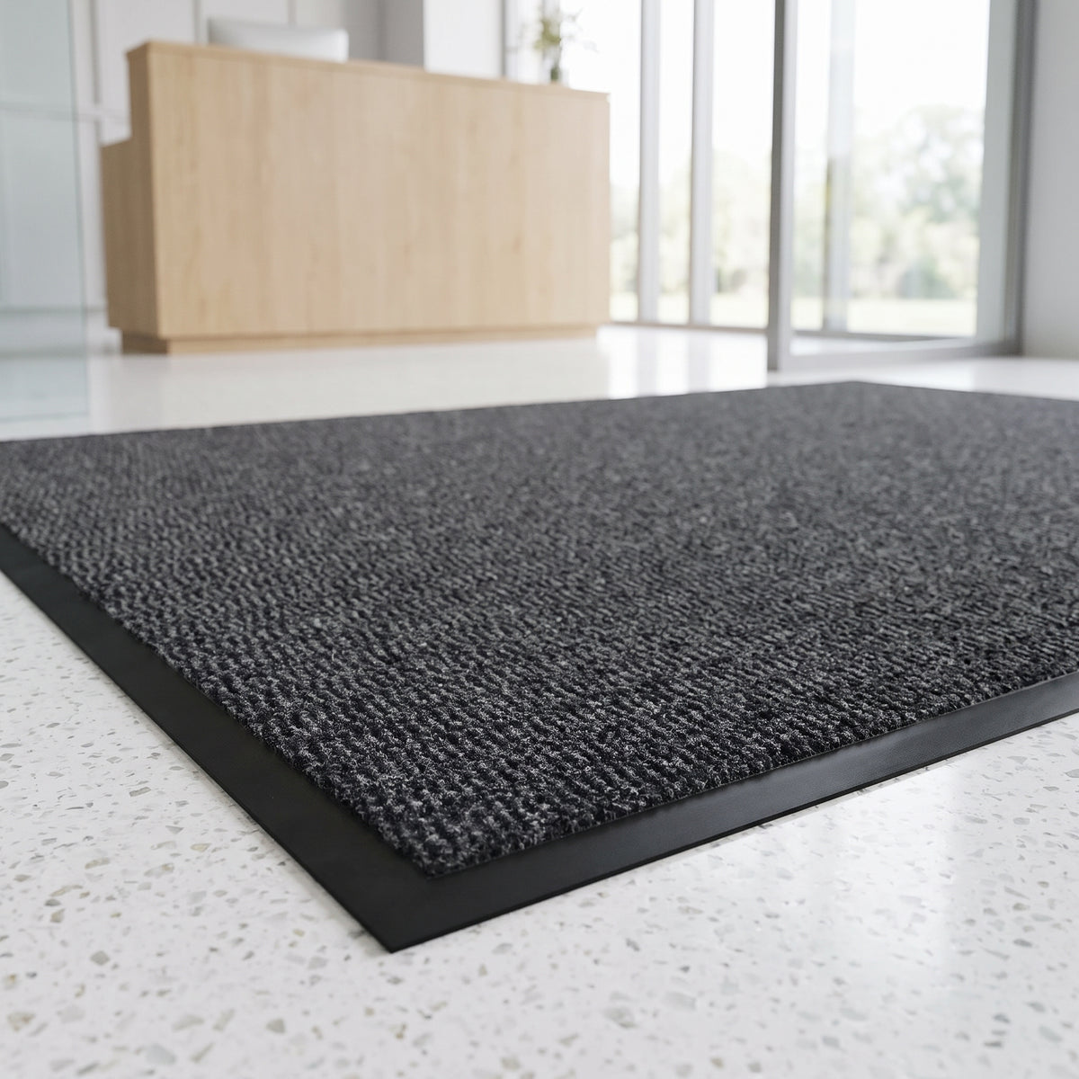 Charcoal low-profile entrance mat at a private clinic reception on terrazzo floor