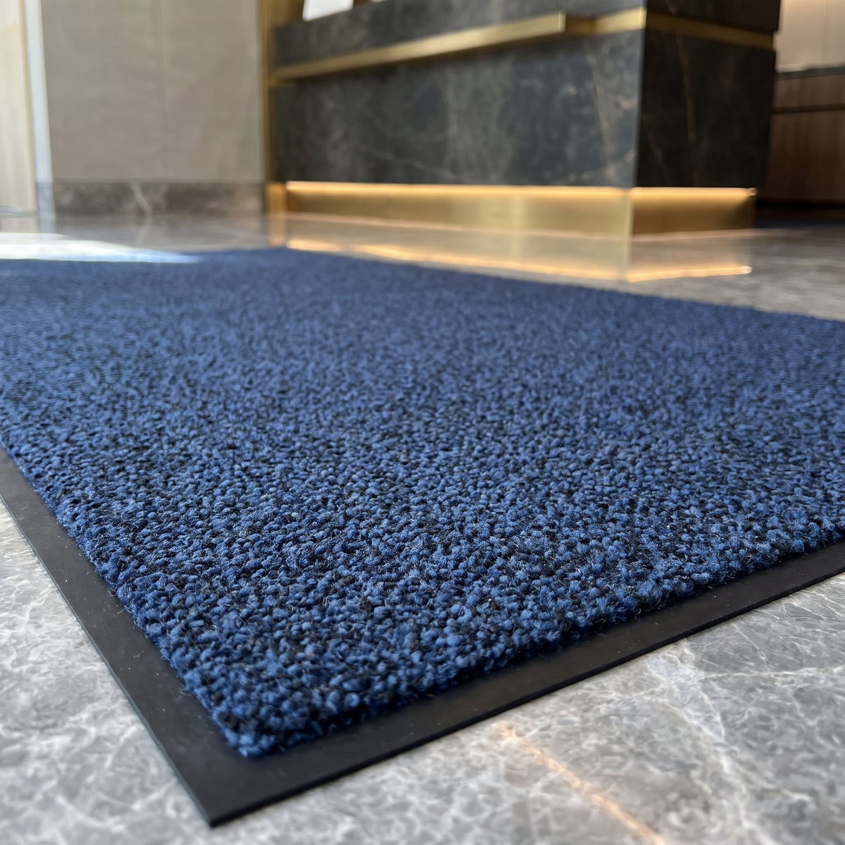 Close-up of Deep Blue luxury made to measure entrance mat in a private bank reception on grey marble
