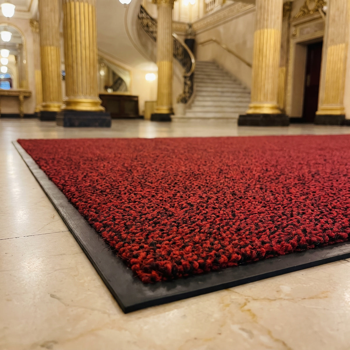 Close-up of Red and Black luxury made to measure entrance mat in a historic theatre foyer on cream marble
