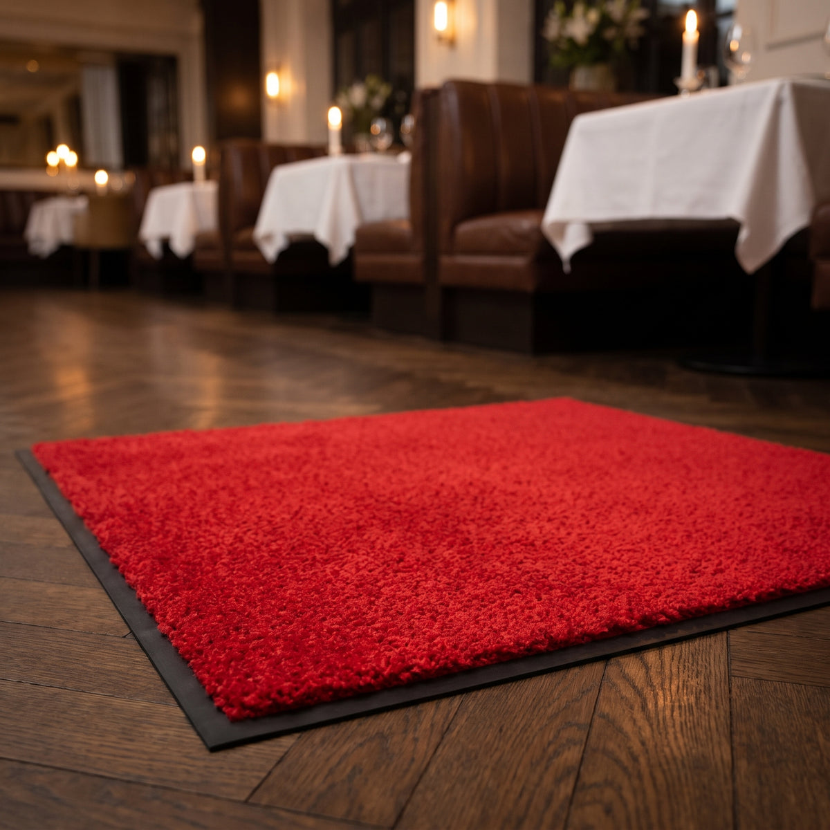 Red commercial made to measure entrance mat at a restaurant entrance on herringbone parquet