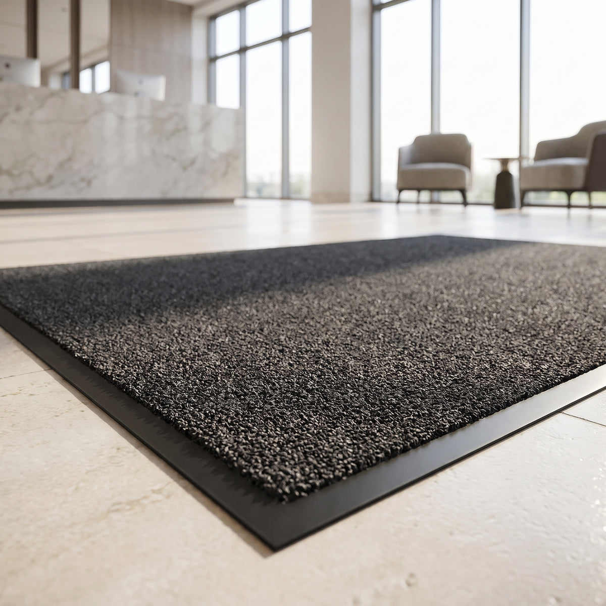 Charcoal machine washable entrance mat with twist pile and rubber edge in a bright hotel lobby