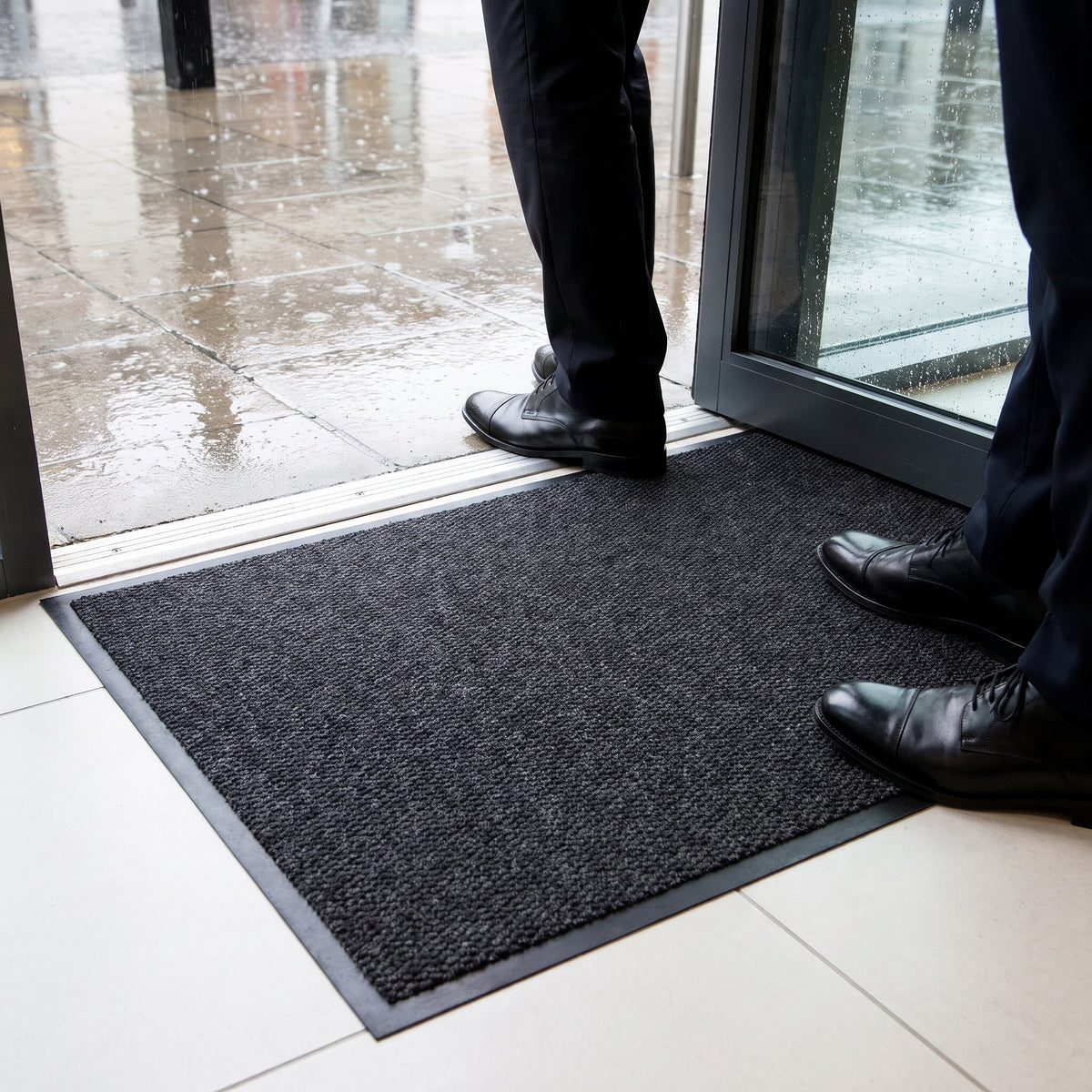 Machine washable entrance mat trapping rainwater from shoes at a busy shop doorway