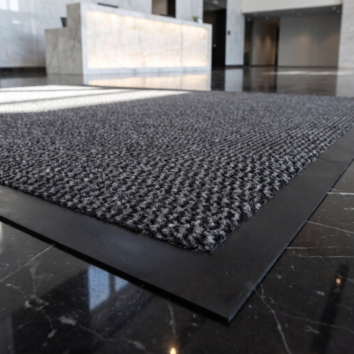 Close-up of grey Slimline entrance mat texture in a corporate headquarters reception on black marble