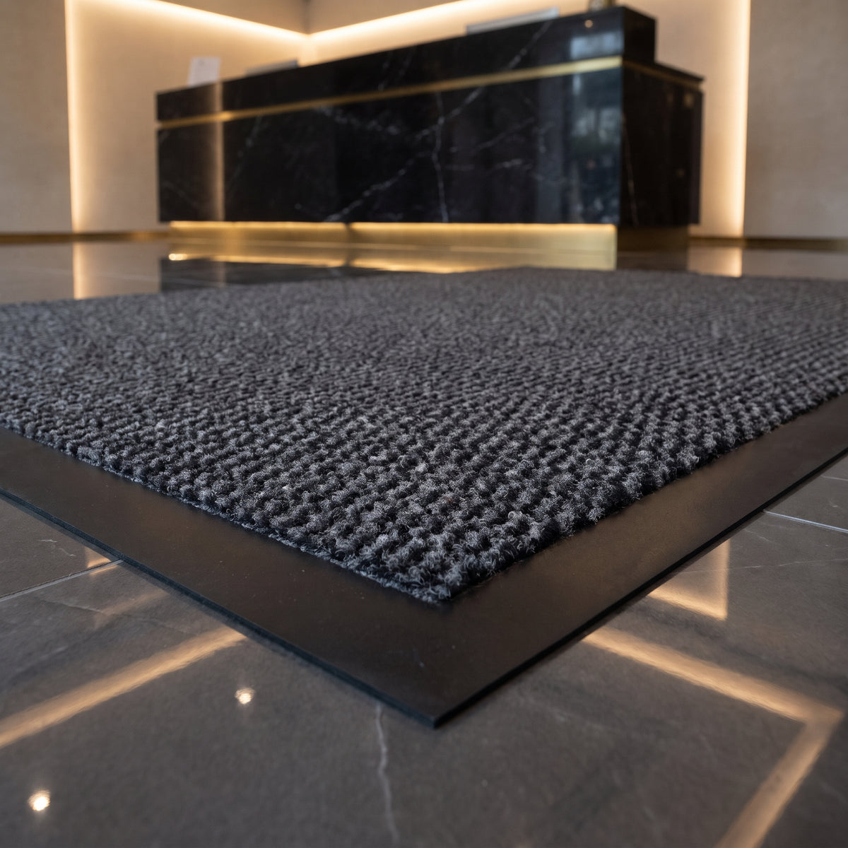 Close-up of grey Slimline entrance mat texture at a luxury gym and spa reception with marble counter