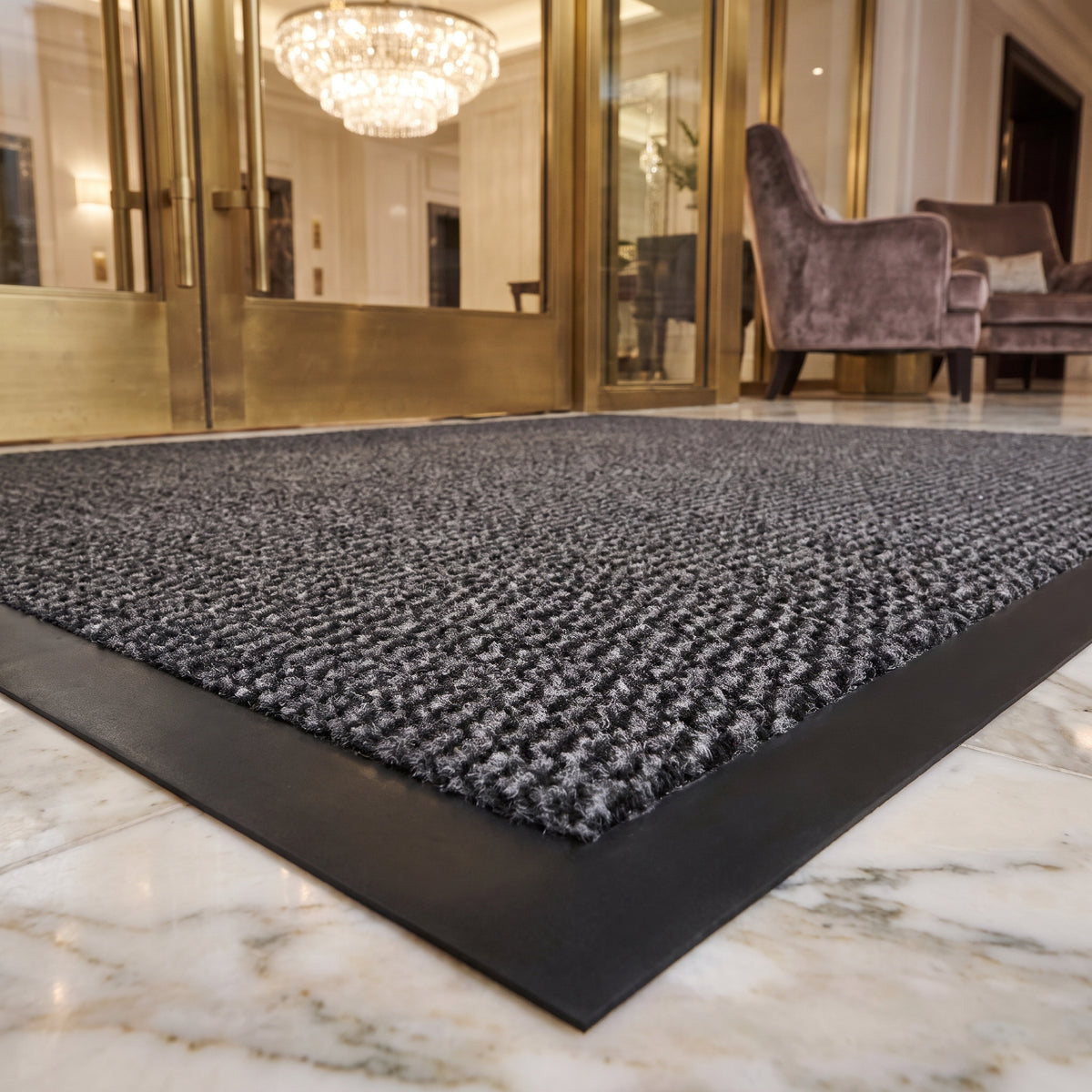 Close-up of grey Slimline entrance mat pile and black border at a luxury hotel lobby entrance on marble